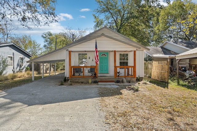bungalow with a porch, driveway, fence, and a carport