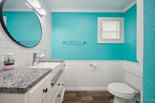 half bath with backsplash, wood finished floors, a healthy amount of sunlight, toilet, and vanity