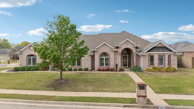 view of front of home featuring a front lawn, brick siding, fence, and a shingled roof