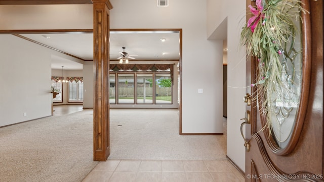 tiled foyer entrance with baseboards, a ceiling fan, decorative columns, and carpet