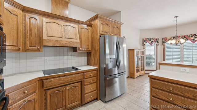 kitchen featuring black electric cooktop, decorative backsplash, stainless steel fridge with ice dispenser, brown cabinetry, and decorative light fixtures
