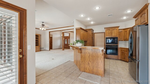 kitchen with a peninsula, light colored carpet, a ceiling fan, black appliances, and light tile patterned floors