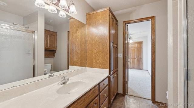 bathroom featuring tile patterned flooring, toilet, vanity, a stall shower, and ceiling fan