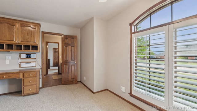 unfurnished office featuring radiator heating unit, baseboards, and light colored carpet
