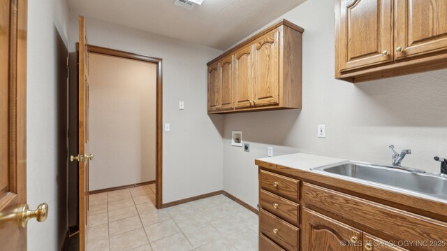 laundry area featuring a sink, electric dryer hookup, cabinet space, baseboards, and washer hookup
