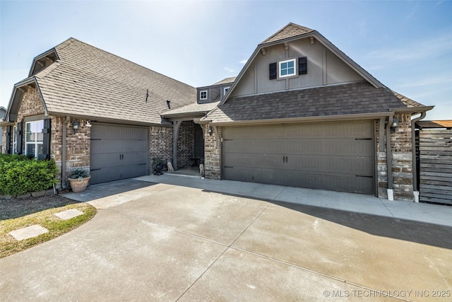 view of front of property with roof with shingles, driveway, stone siding, brick siding, and an attached garage