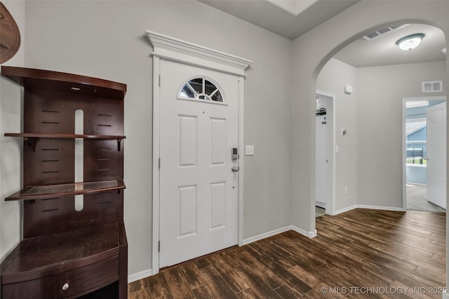 foyer with arched walkways, dark wood finished floors, visible vents, and baseboards