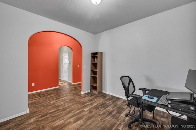 office with arched walkways, wood finished floors, and baseboards