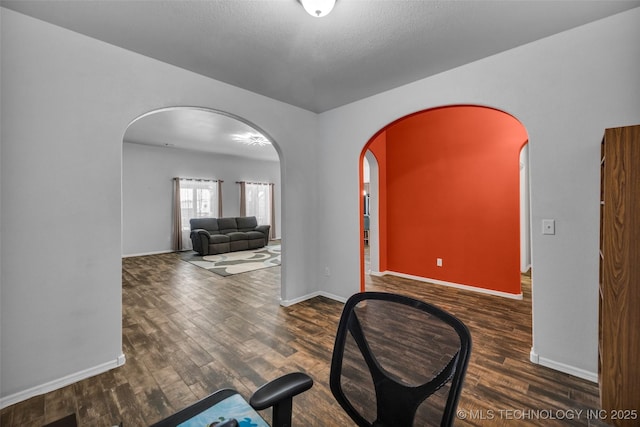 foyer entrance featuring arched walkways, wood finished floors, and baseboards