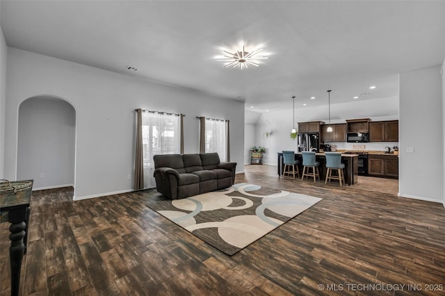 living room featuring arched walkways, baseboards, visible vents, recessed lighting, and dark wood-type flooring