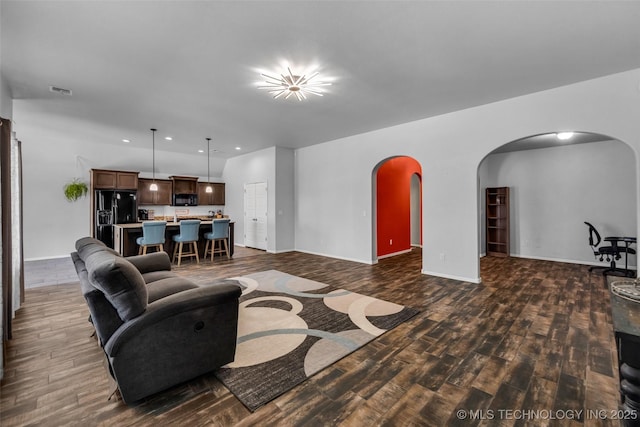 living area with recessed lighting, dark wood finished floors, visible vents, arched walkways, and baseboards