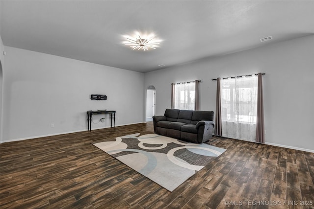 living room featuring arched walkways, wood finished floors, visible vents, and baseboards