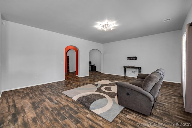 living room with arched walkways, wood finished floors, visible vents, and baseboards