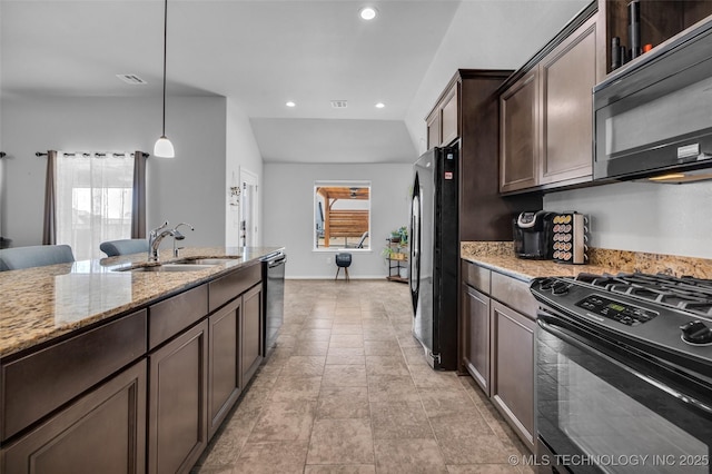 kitchen with light stone counters, a sink, hanging light fixtures, black appliances, and dark brown cabinetry