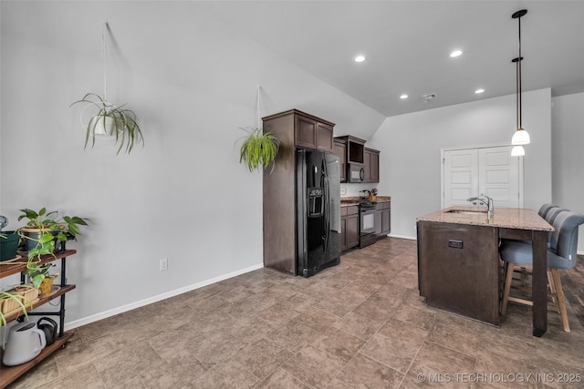 kitchen with dark brown cabinets, black appliances, a kitchen bar, baseboards, and light stone countertops