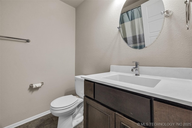 full bath with toilet, vanity, and baseboards