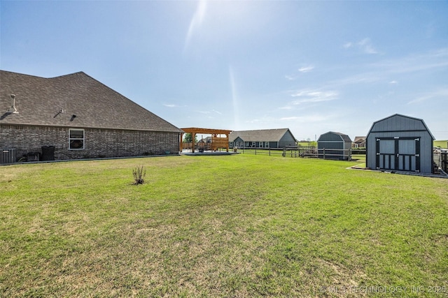 view of yard featuring fence, a storage unit, an outdoor structure, and central AC