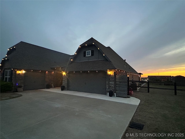 view of front of property featuring stone siding, fence, a garage, and concrete driveway