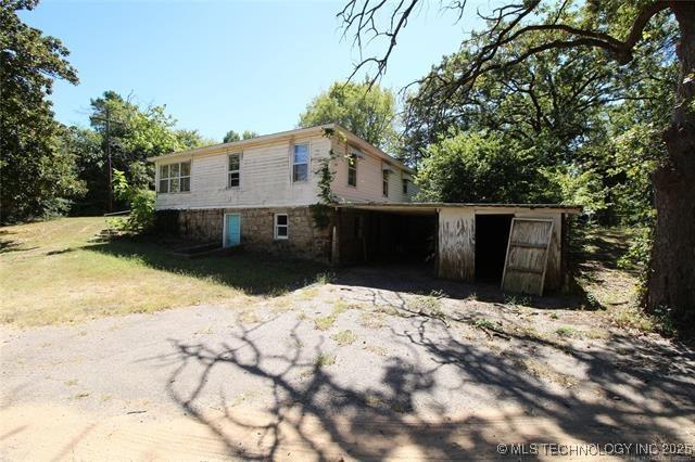 988 Wilson St, Durant, OK 74701 - view of side of home with a carport, a lawn, and driveway