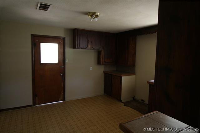 988 Wilson St, Durant, OK 74701 - kitchen featuring dark brown cabinets, baseboards, visible vents, and light colored carpet