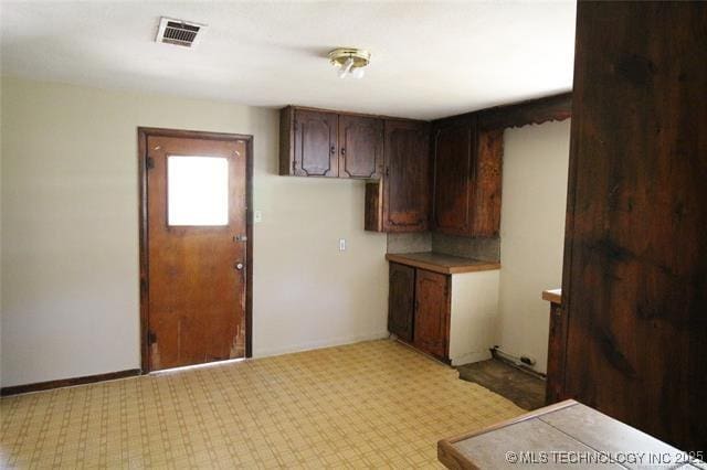988 Wilson St, Durant, OK 74701 - kitchen with light carpet, dark brown cabinetry, visible vents, and baseboards