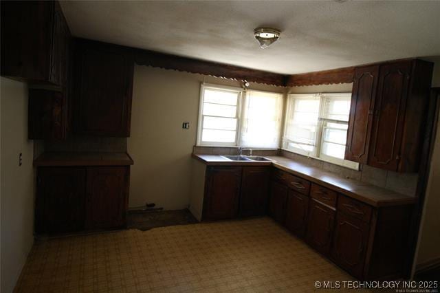 988 Wilson St, Durant, OK 74701 - kitchen with dark brown cabinetry, tile counters, a sink, and a wealth of natural light