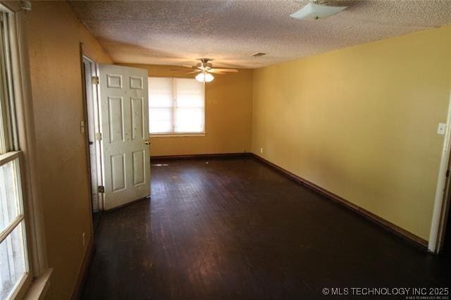 988 Wilson St, Durant, OK 74701 - unfurnished room with a textured ceiling, a ceiling fan, baseboards, and dark wood-style flooring