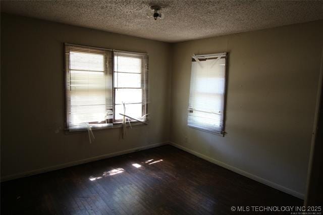 988 Wilson St, Durant, OK 74701 - unfurnished room with dark wood finished floors, baseboards, a healthy amount of sunlight, and a textured ceiling