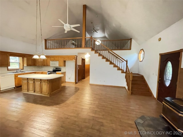 kitchen featuring a center island, a ceiling fan, white appliances, light countertops, and high vaulted ceiling