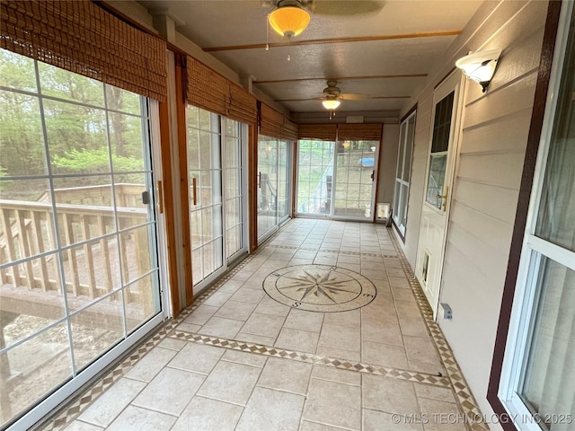 unfurnished sunroom with a ceiling fan and tile patterned floors