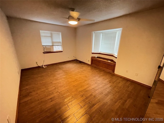 spare room featuring baseboards, wood finished floors, a textured ceiling, and ceiling fan