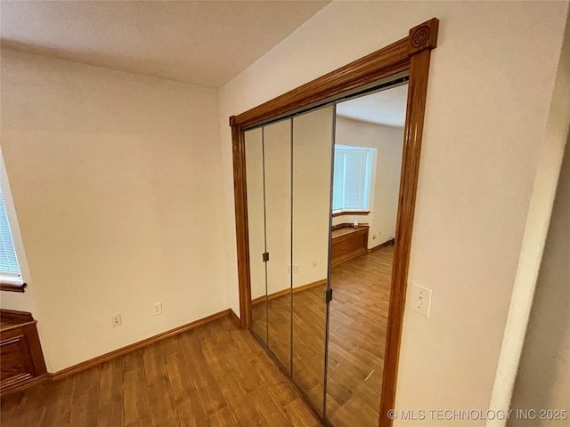 corridor featuring wood finished floors and baseboards