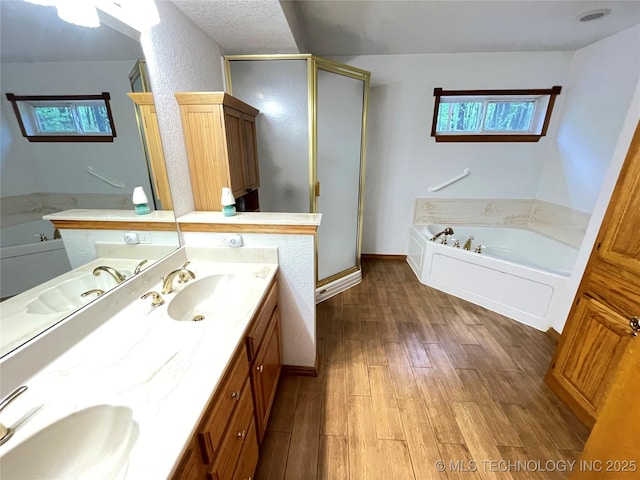 bathroom featuring a bath, wood finished floors, a sink, and double vanity