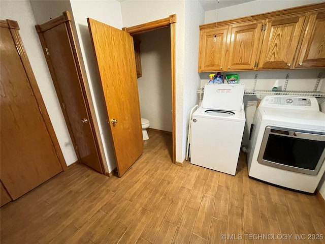 laundry room with cabinet space, light wood-style flooring, and separate washer and dryer