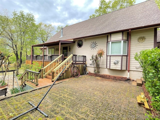ranch-style home with a wooden deck, roof with shingles, and stairs