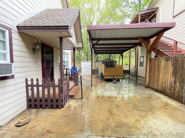 view of patio / terrace featuring fence, a carport, an outbuilding, and a shed