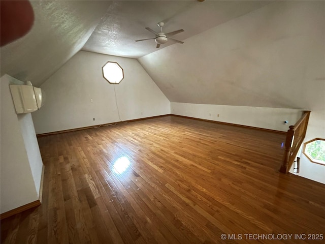 bonus room featuring wood finished floors, lofted ceiling, baseboards, and a ceiling fan