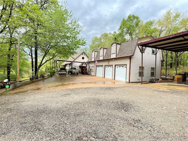 exterior space with driveway, a shingled roof, and a garage