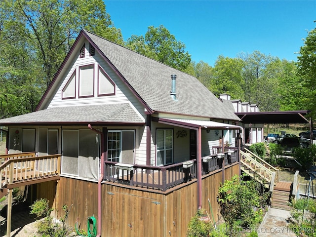 rear view of property featuring roof with shingles, stairs, and a sunroom