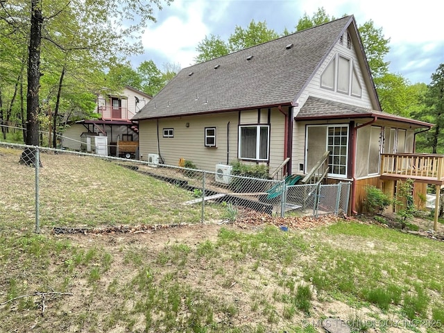 back of property featuring a sunroom, a shingled roof, a fenced backyard, and a lawn