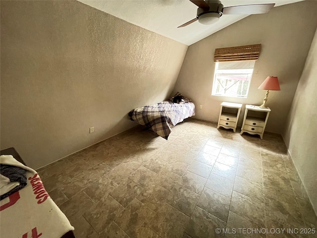 unfurnished bedroom with a ceiling fan, lofted ceiling, and stone tile floors