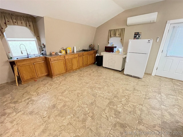 kitchen featuring a wall mounted air conditioner, vaulted ceiling, a sink, freestanding refrigerator, and brown cabinetry