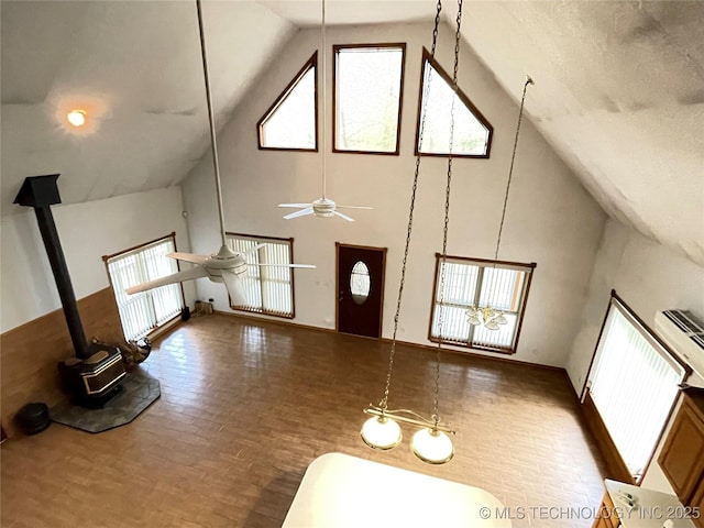 interior space featuring high vaulted ceiling, ceiling fan, and a wood stove