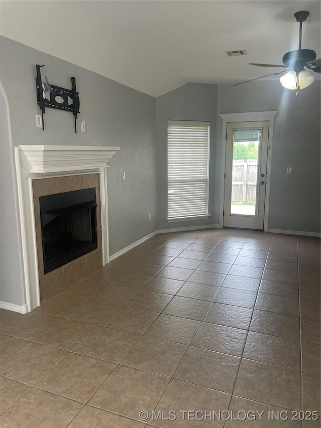 unfurnished living room featuring tile patterned floors, a tiled fireplace, visible vents, lofted ceiling, and ceiling fan