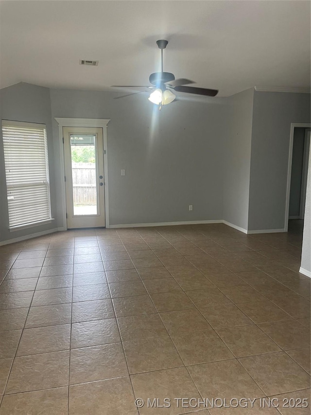 tiled empty room with lofted ceiling, visible vents, baseboards, and ceiling fan