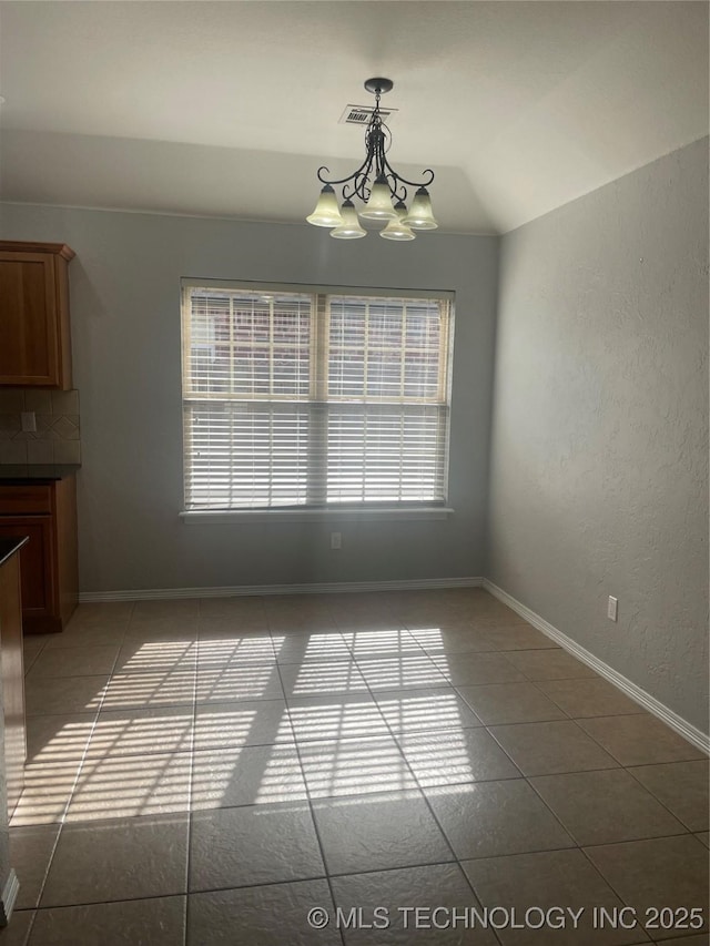 unfurnished dining area featuring an inviting chandelier, vaulted ceiling, visible vents, and tile patterned flooring