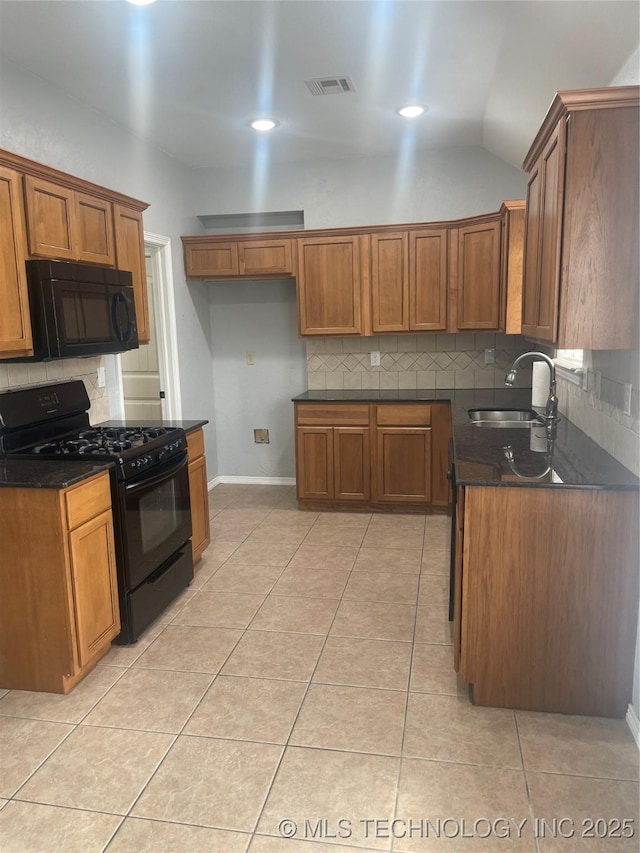 kitchen with dark countertops, visible vents, a sink, and black appliances