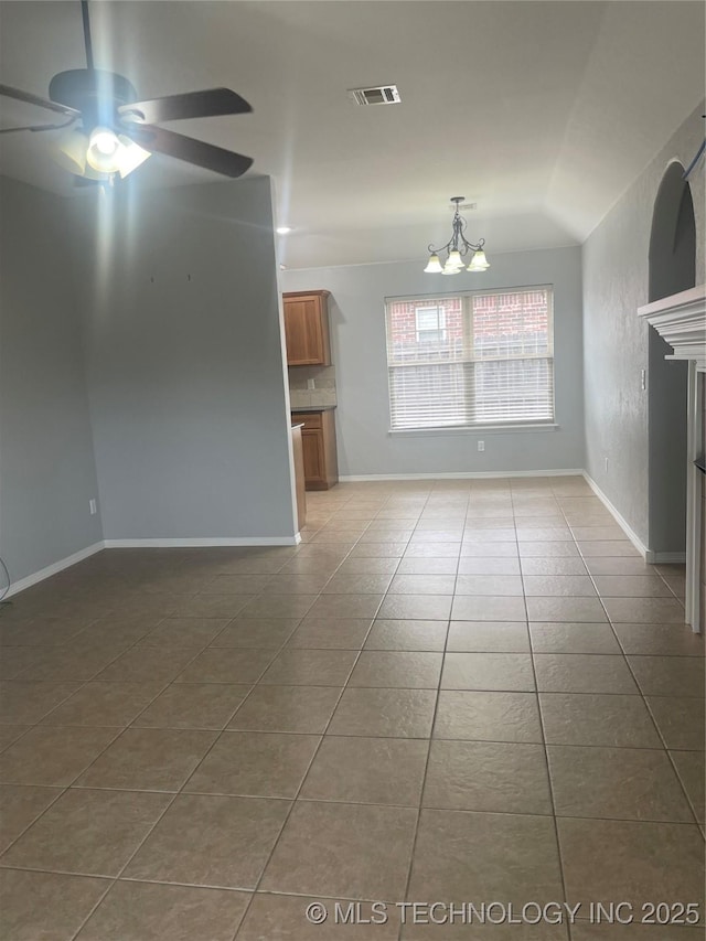 unfurnished living room featuring baseboards, visible vents, ceiling fan with notable chandelier, tile patterned flooring, and a fireplace