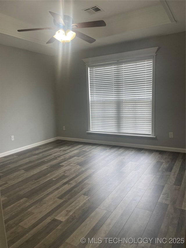 empty room featuring visible vents, baseboards, dark wood-type flooring, and ceiling fan