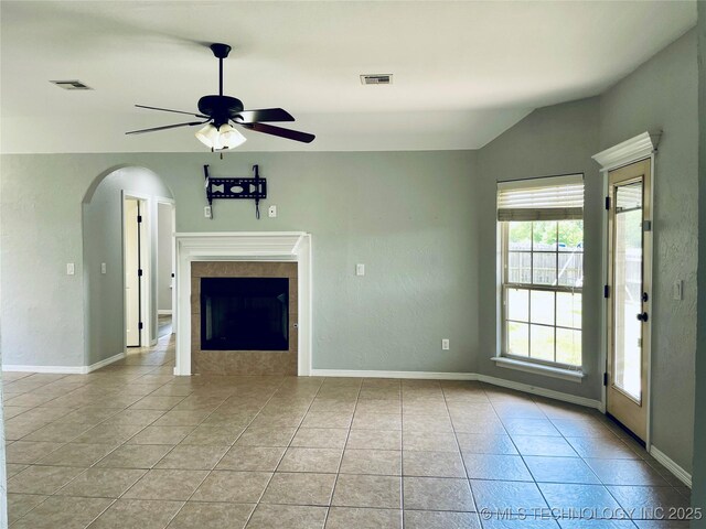 9700 E 110th St N, Owasso, OK 74055 - unfurnished living room with a ceiling fan, light tile patterned floors, arched walkways, a tile fireplace, and lofted ceiling